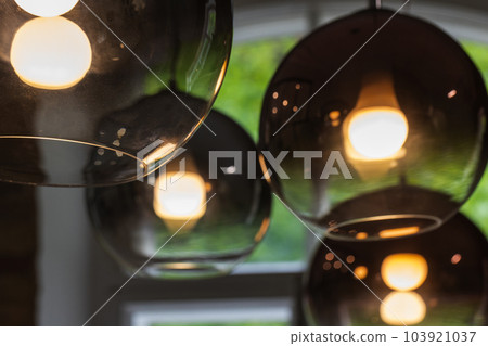 Round glass lampshades with  glowing tungsten lamps inside, close-up 103921037