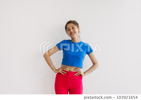 Happy woman in colorful clothes standing with arms on the hips or akimbo. 103921654