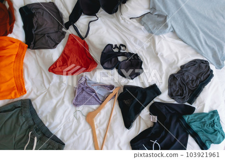 Cluttered and untidy apartment bed room full of colorful clothes everywhere. 103921961