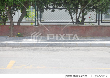 A street border painted in white and black on the background of the road and green foliage in the summer closeup. Road safety, minimalism. A street border painted in white and black on the background of the road and green foliage in the summer closeup. Road safety, minimalism. 103922057