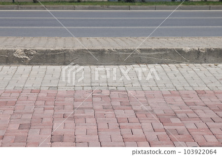 A street border painted in white and black on the background of the road and green foliage in the summer closeup. Road safety, minimalism. A street border painted in white and black on the background of the road and green foliage in the summer closeup. Road safety, minimalism. 103922064