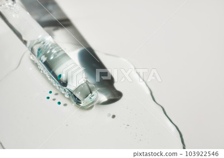 Pipette and drop of cosmetic product with blue particles, selective focus Pipette and drop of cosmetic product with blue particles, selective focus 103922546