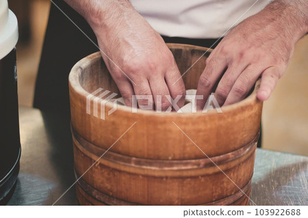 Close-up of hands of a unrecognizable sushi chef cooking rice in a traditional wooden Asian steamer basin or bucket Close-up of hands of a unrecognizable sushi chef cooking rice in a traditional wooden Asian steamer basin or bucket 103922688