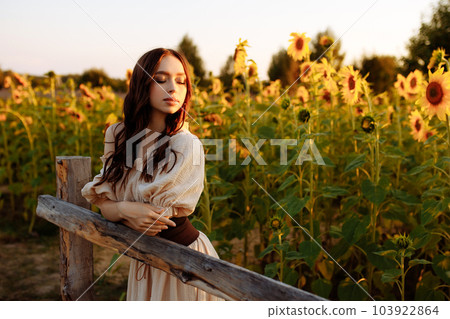 Beautiful woman in a dress in a field of sunflowers 103922864