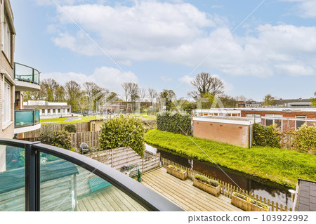 a balcony with green roofing and grass on the lawn in front of the house, as seen from an apartment window 103922992