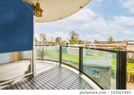 a balcony with blue sky and white clouds in the background, as seen from an apartment's upper deck 103922993