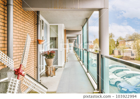 a balcony with chairs and flowers on the railing, in front of a brick building that has been painted white a balcony with chairs and flowers on the railing, in front of a brick building that has been painted white 103922994