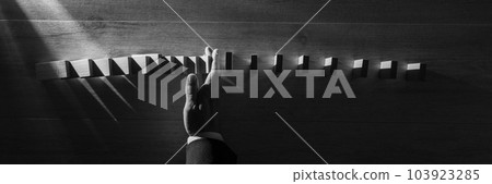 Wide panorama top view of businessman stopping falling blocks Wide panorama top view of businessman stopping falling blocks 103923285