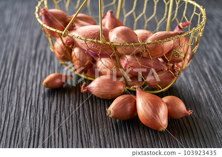 onion shallots in a basket on a black wooden table, selective focus. 103923435