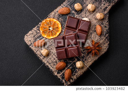 Delicious sweet black chocolate broken into cubes on a wooden cutting board Delicious sweet black chocolate broken into cubes on a wooden cutting board 103923482