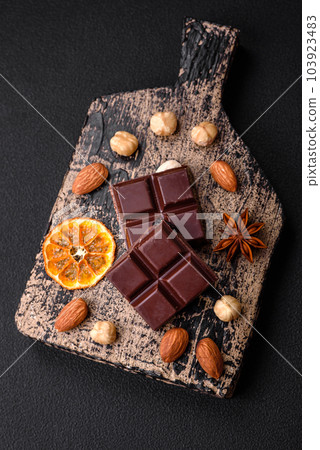 Delicious sweet black chocolate broken into cubes on a wooden cutting board Delicious sweet black chocolate broken into cubes on a wooden cutting board 103923483