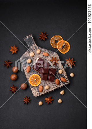 Delicious sweet black chocolate broken into cubes on a wooden cutting board Delicious sweet black chocolate broken into cubes on a wooden cutting board 103923488