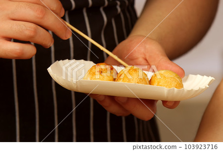 A chef sticks a portion of deep-fried dumplings into a paper box. 103923716