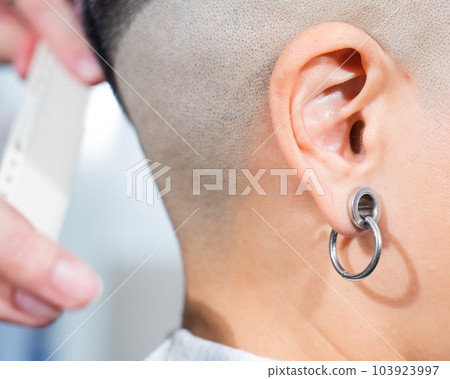 Close-up of a woman's ear with a small tunnel. Close-up of a woman's ear with a small tunnel. 103923997