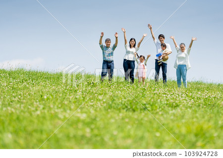 A three-generation family standing on a blue sky hill A three-generation family standing on a blue sky hill 103924728