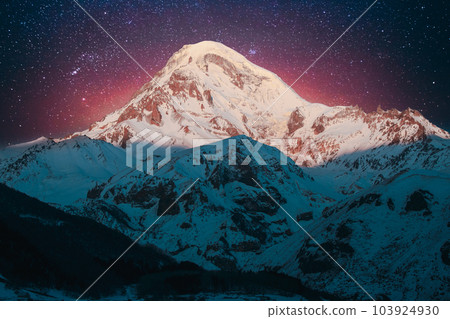 Georgia. Winter Bold Bright Night Starry Violet Gradient Sky With Glowing Stars Over Peak Of Mount Kazbek Covered With Snow. Amazing Night Georgian Winter Landscape. Travel To Georgia 103924930
