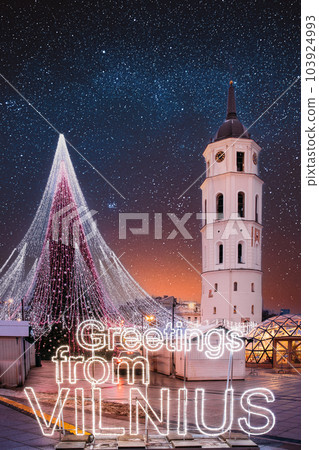 Vilnius, Lithuania. Bell Tower Belfry Of Vilnius Cathedral At Square In Evening New Year Christmas Xmas Illuminations. Amazing Bold Bright Blue Starry Sky Gradient Above Christmas Tree On Background Vilnius, Lithuania. Bell Tower Belfry Of Vilnius Cathedral At Square In Evening New Year Christmas Xmas Illuminations. Amazing Bold Bright Blue Starry Sky Gradient Above Christmas Tree On Background 103924993