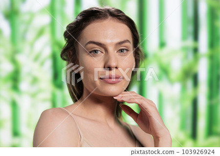 Beautiful smiling woman with fresh skin after using herbal facial cosmetics portrait. Attractive young skincare treatment model holding hand under chin and looking at camera 103926924