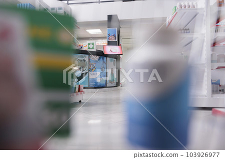 Selective focus of pharmacy counter desk filled with pharmaceutical products and computer, health space waiting for customers to come and buy pills. Drugstore shelves were stocked with drugs packages. Selective focus of pharmacy counter desk filled with pharmaceutical products and computer, health space waiting for customers to come and buy pills. Drugstore shelves were stocked with drugs packages. 103926977