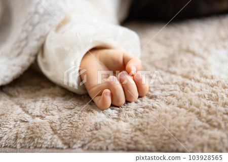The right hand of an infant taking a nap in the living room 103928565