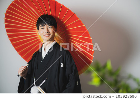 一個穿著帶徽章的袴的男人,一把日本傘 一個穿著帶徽章的袴的男人,一把日本傘 103928696