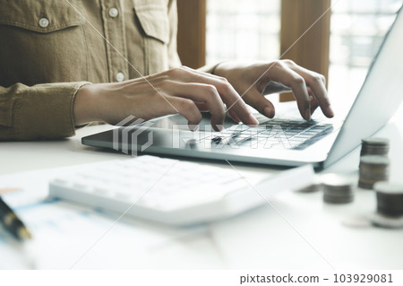 Woman accountant working on laptop computer while counting taxes online. 103929081
