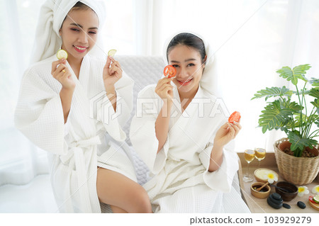 Asia women friends relaxing enjoy and spa massage with facial masks tomato put on bathrobe. Asia women friends relaxing enjoy and spa massage with facial masks tomato put on bathrobe. 103929279