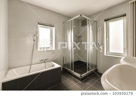 a modern bathroom with black and white tile flooring, large walk - in shower and free standing bathtub 103930179