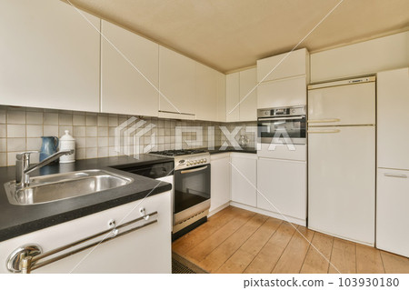 a kitchen with white cupboards and black counter tops on the counters in this photo is taken from the inside a kitchen with white cupboards and black counter tops on the counters in this photo is taken from the inside 103930180
