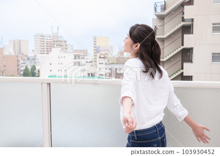 在陽台上深吸一口氣的年輕女子 103930452