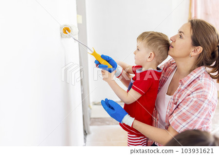 Mother and child son paint the wall with paint using roller and brush Mother and child son paint the wall with paint using roller and brush 103931621