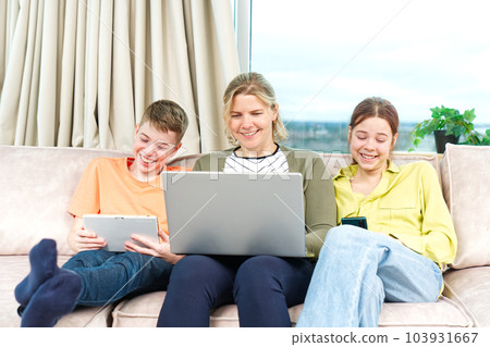 Happy Family on couch using gadget. Rest at home. Using Digital devices at home Happy Family on couch using gadget. Rest at home. Using Digital devices at home 103931667