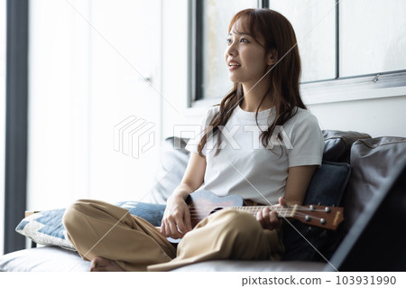 Woman playing ukulele in her room 103931990