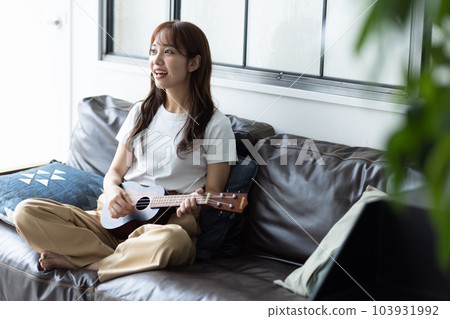 Woman playing ukulele in her room Woman playing ukulele in her room 103931992