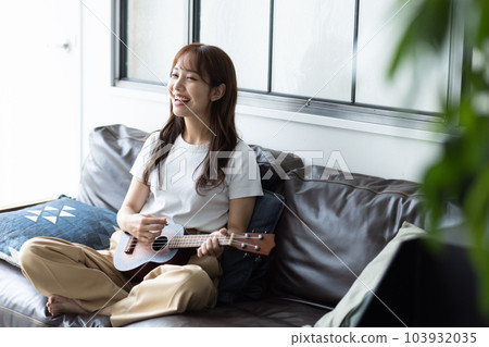 Woman playing ukulele in her room 103932035