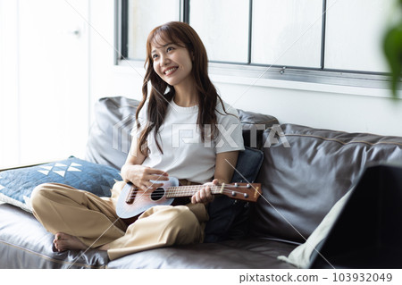 Woman playing ukulele in her room 103932049