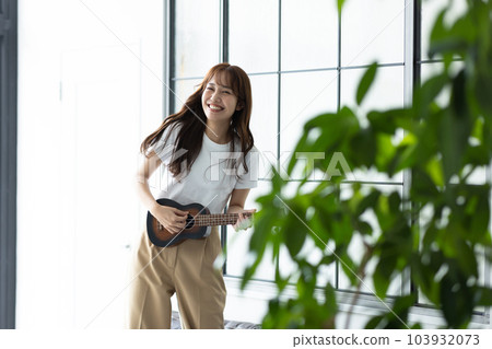 Woman playing ukulele in her room 103932073