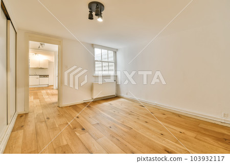 an empty living room with wood flooring and white walls in the room is very clean, but there is no furniture an empty living room with wood flooring and white walls in the room is very clean, but there is no furniture 103932117
