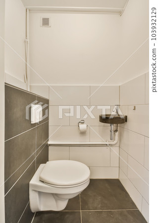 a white toilet in a bathroom with black and white tiles on the wall behind it, there is a trash can be seen a white toilet in a bathroom with black and white tiles on the wall behind it, there is a trash can be seen 103932129