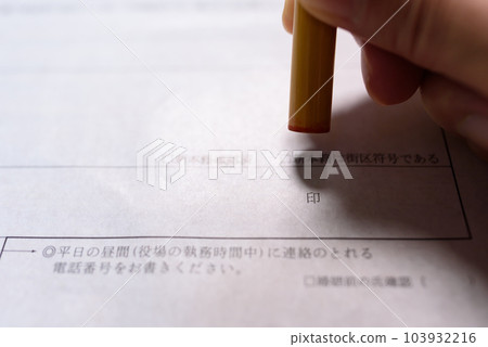 Hand holding a stamp on an official document Sealing a registered seal Hand holding a stamp on an official document Sealing a registered seal 103932216