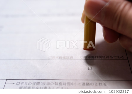 Hand holding a stamp on an official document Sealing a registered seal 103932217