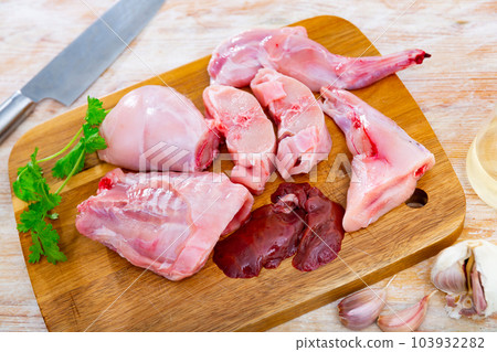 Chopped fresh raw rabbit with greens, garlic and spices on wooden cutting board Chopped fresh raw rabbit with greens, garlic and spices on wooden cutting board 103932282