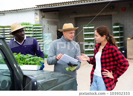 Girl manager discussing with workers delivery of seedlings to farm 103932333
