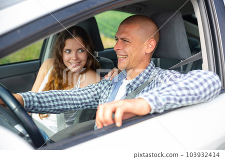 Attractive young woman and man talking and smiling in car 103932414