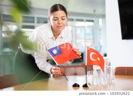 Woman secretary prepares an office for negotiations - she places flags of Taiwan and Turkish table 103932622