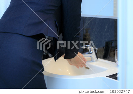A woman's hand washing her hands with a tap Business woman A woman's hand washing her hands with a tap Business woman 103932747