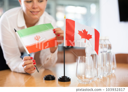 Unrecognizable girl sets midget flags of Canada and Iran before international negotiations Unrecognizable girl sets midget flags of Canada and Iran before international negotiations 103932817