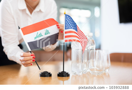 Female hands placing flags of Iraq and United States on table 103932888