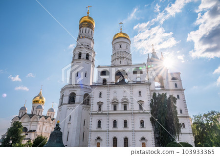 Ivan the Great Bell Tower, with Assumption Belfry on the right in Moscow Kremlin. Blue sky background with sunbeams 103933365