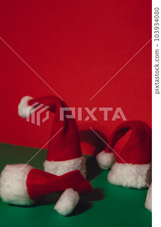 Santa hats on isometric green red background. Copy space for your text. Mock up for advertisement. Holiday Christmas composition. Minimalistic greeting card 103934080